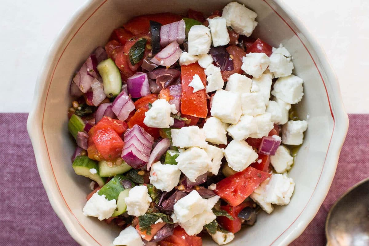 Tomato and cucumber salad with feta in bowl.