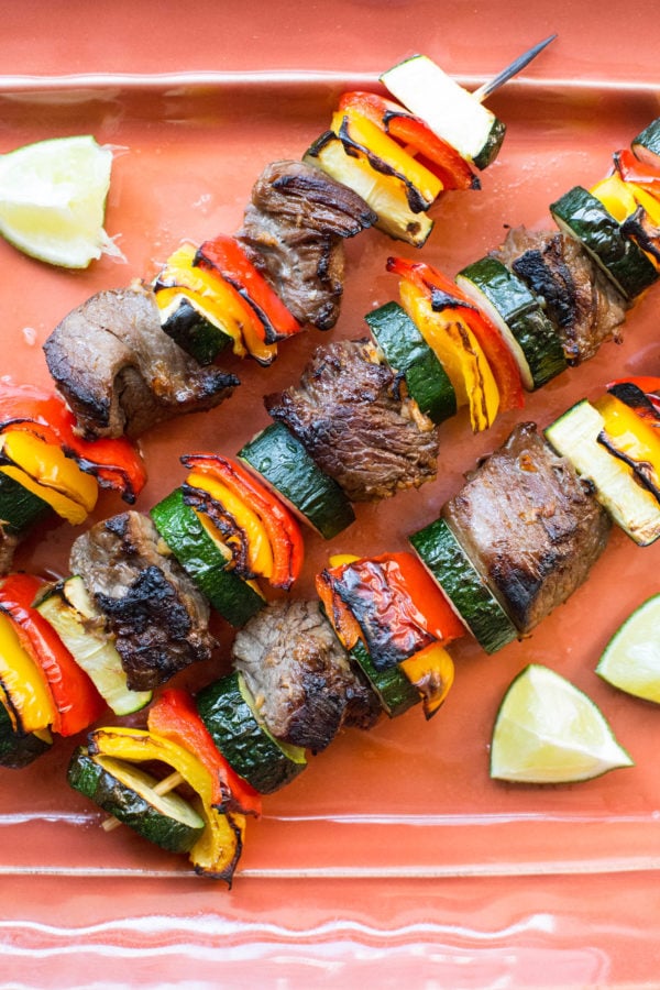 Salmon-colored tray of Beef Teriyaki Kebabs with Peppers and Zucchini.