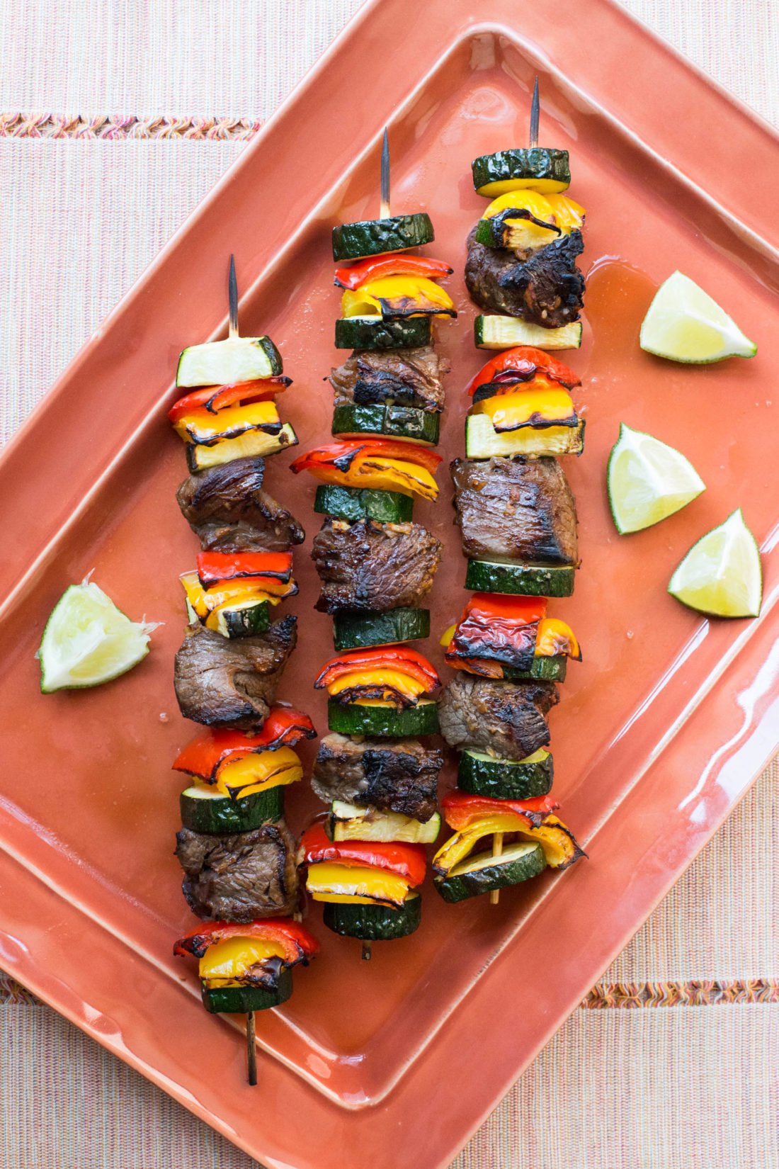 Three Beef Teriyaki Kebabs with Peppers and Zucchini on a tray.