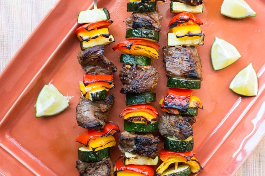 Beef Teriyaki Kebabs with Peppers and Zucchini on a salmon-colored tray.