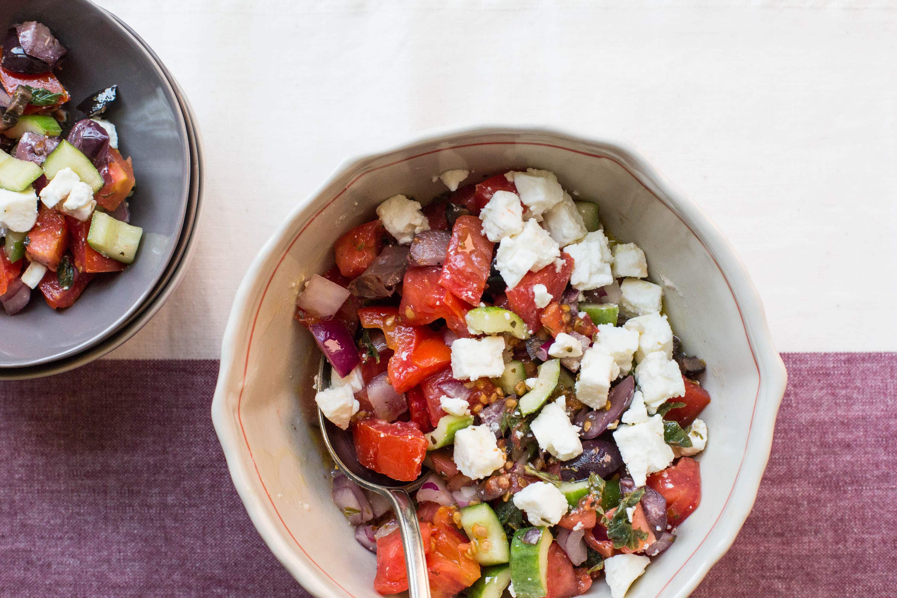 Bowls of Greek Tomato and Cucumber Salad on table.