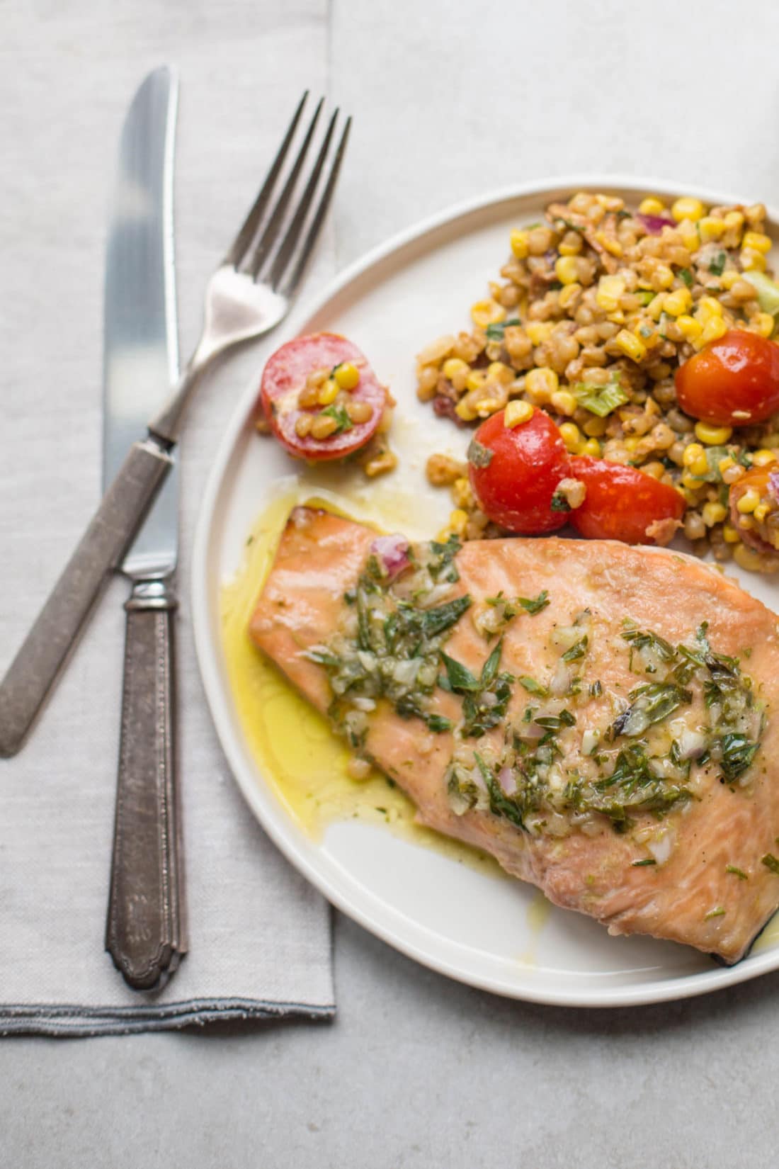 Silverware next to a plate of Salmon with Tarragon Vinaigrette and grain salad.