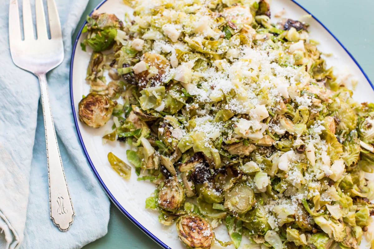 Plate of Brussels Sprouts Three Ways topped with grated cheese.