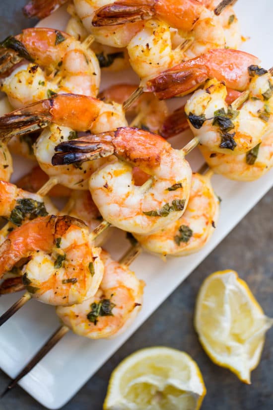 Plate of Citrus Basil Shrimp Kebabs next to a lemon wedge.