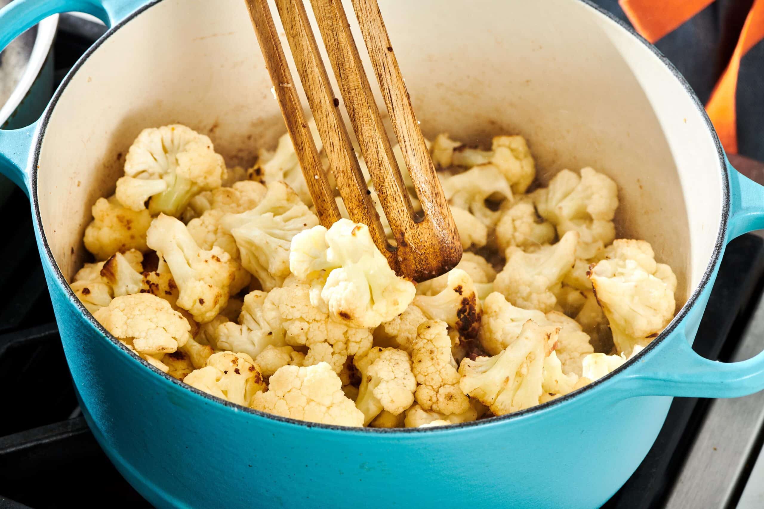 Cauliflower and a wooden spatula in a Dutch Oven.