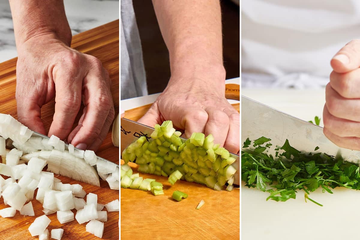 Chopping white onion, celery, and parsley on cutting board with knife.