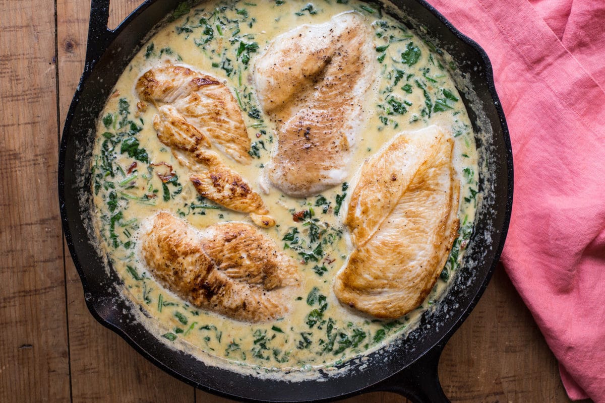 Creamy Spinach, Sundried Tomato and Garlic Chicken in cast-iron skillet on table.