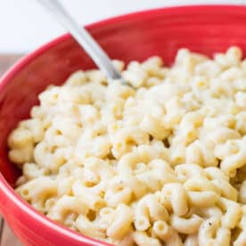 Red bowl filled with homemade white macaroni and cheese.