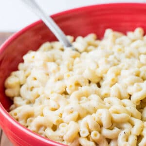 Red bowl filled with homemade white macaroni and cheese.