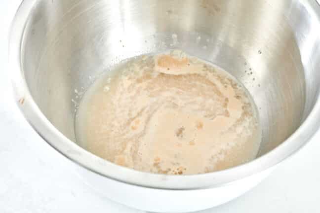Yeast, sugar, and water in a metal bowl.
