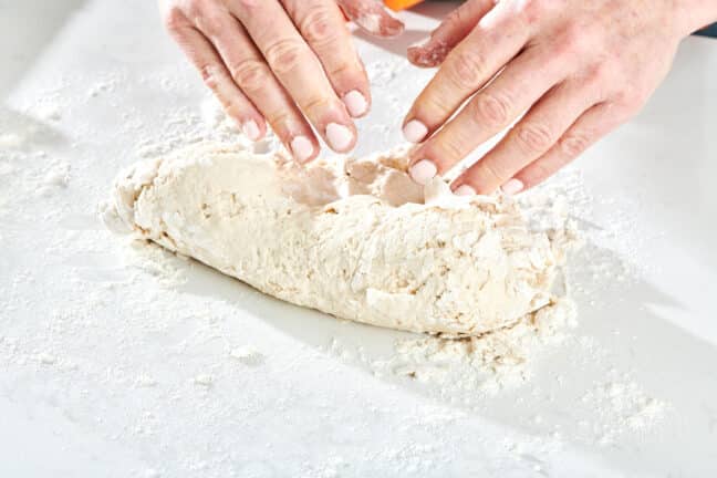 Woman kneading Pizza Dough on a floured surface.