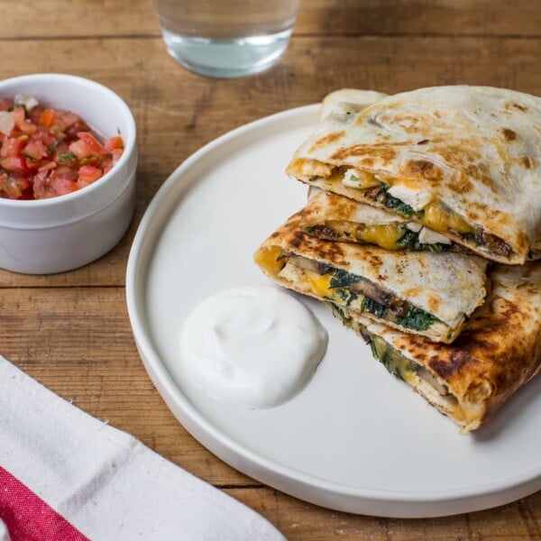 Plate of Spinach, Mushroom, and Chicken Quesadillas on a wooden table.