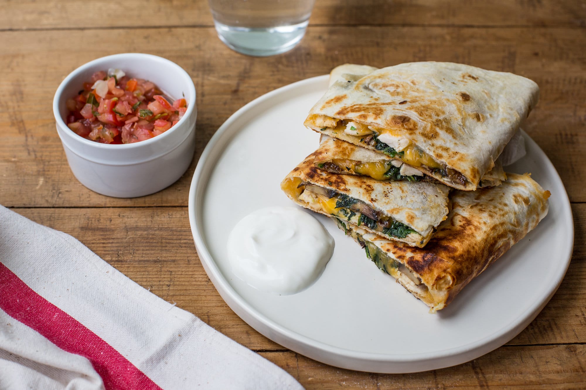 Chicken, Spinach and Mushroom Quesadillas  on a whit e plate with salsa nearby.