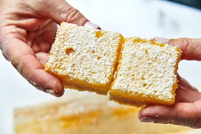 Woman holding two Lemon Squares.