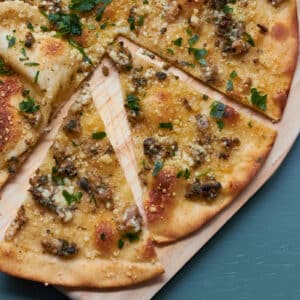 Clam Pizza on a wooden pizza board.