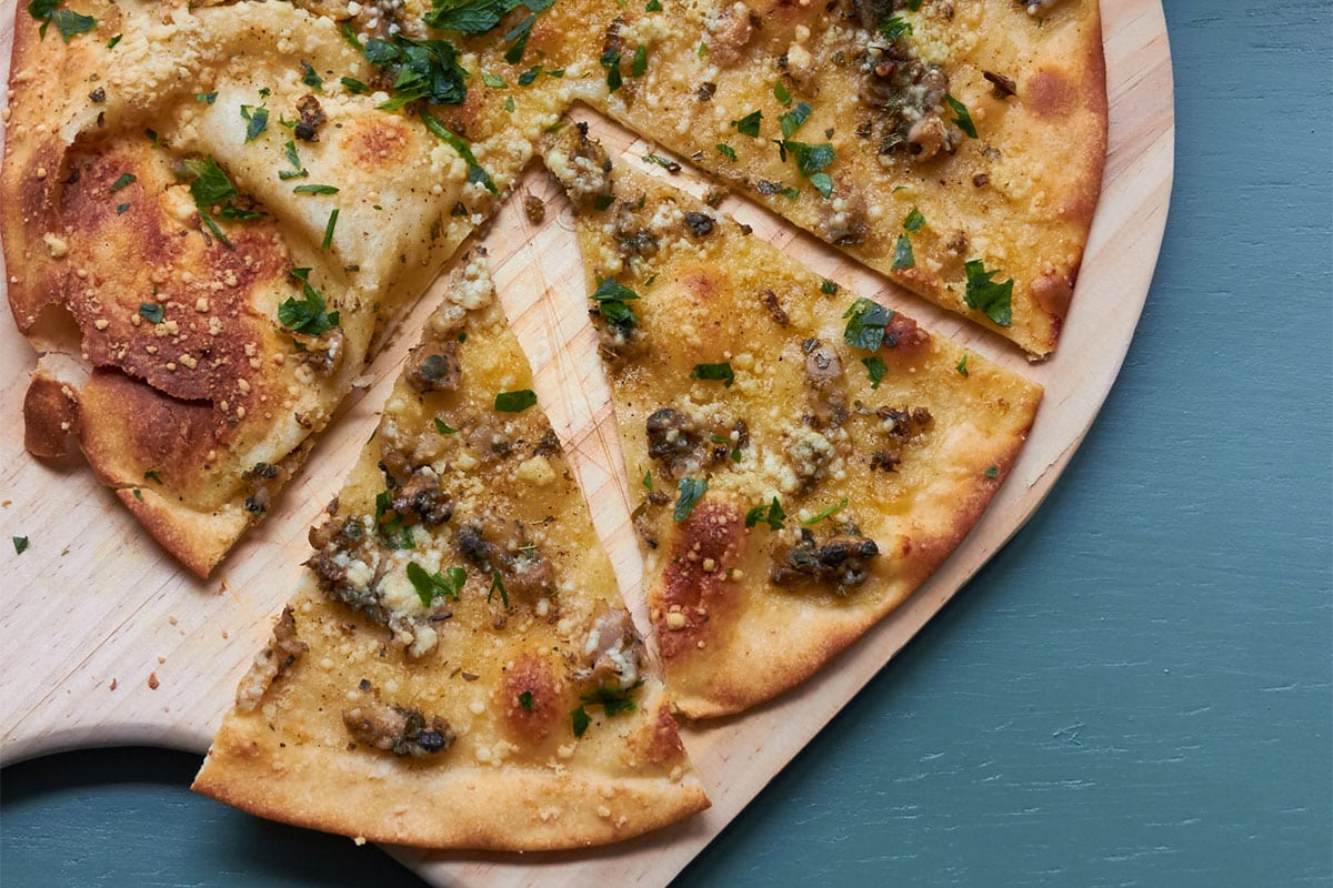 Clam Pizza on a wooden pizza board.