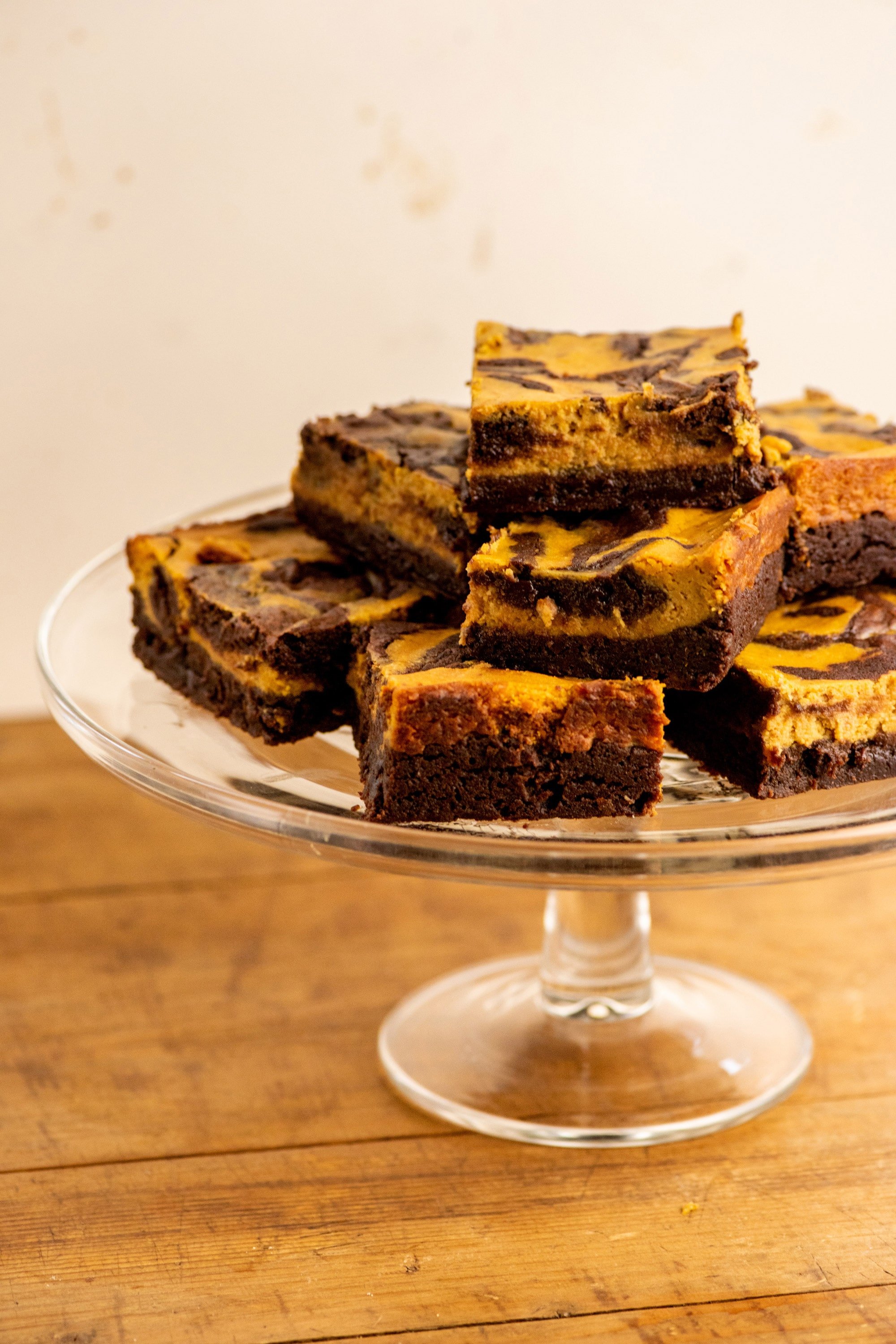 Pumpkin Cream Cheese Brownies piled on a glass serving dish.