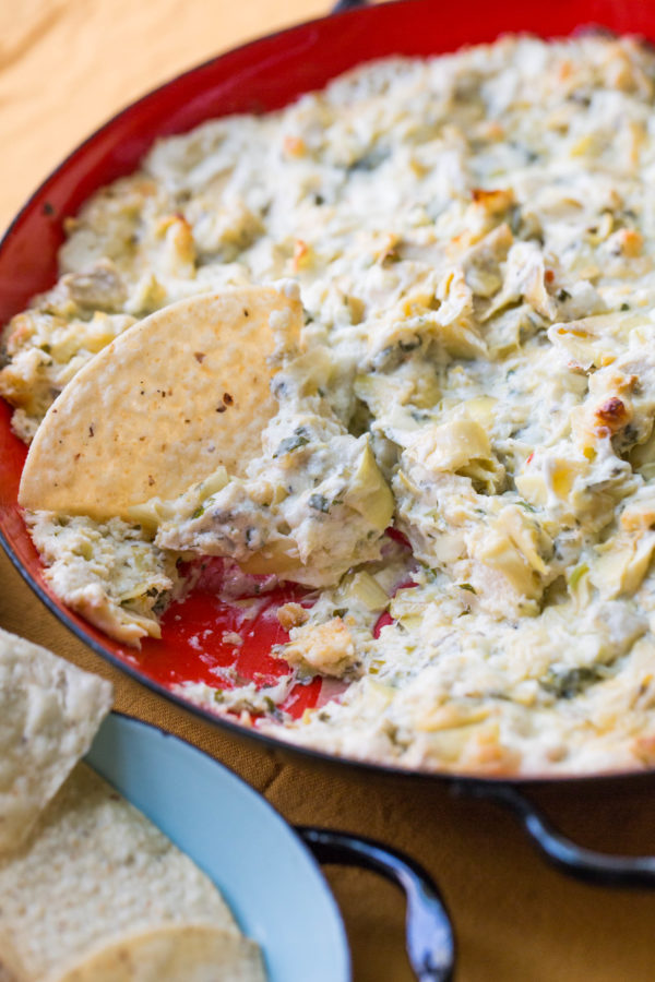 Spicy Cheesy Artichoke Dip with a chip sticking out.