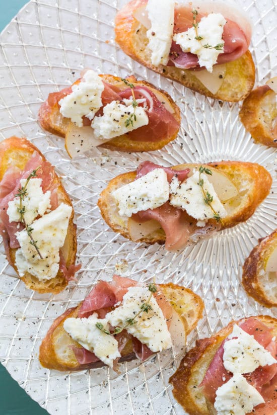 Prosciutto, Asian Pear and Blue Cheese Crostini on a sparkly white plate.