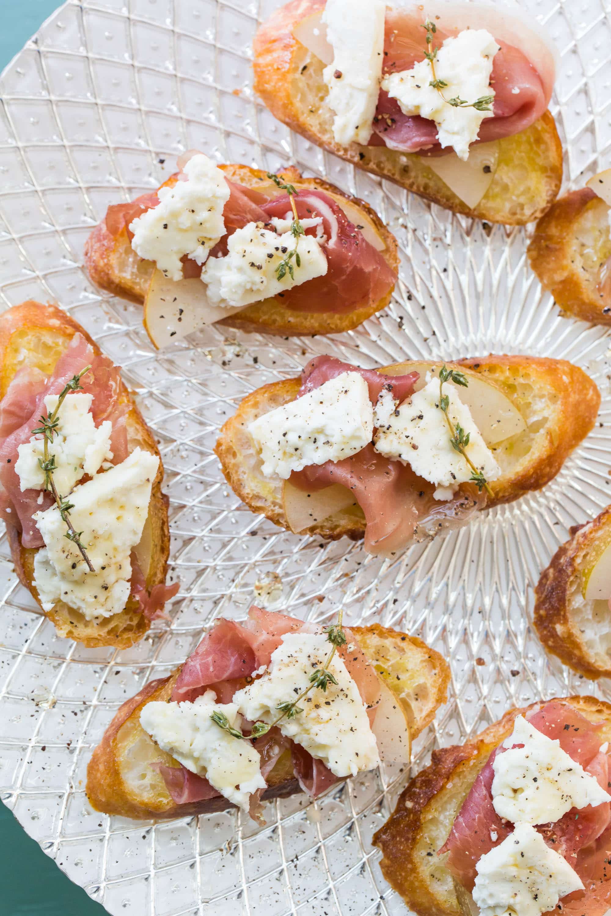 Prosciutto, Asian Pear and Blue Cheese Crostini on a glass plate.