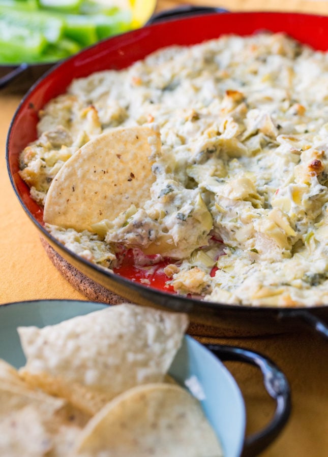 Chip in a bowl of Spicy Cheesy Artichoke Dip.