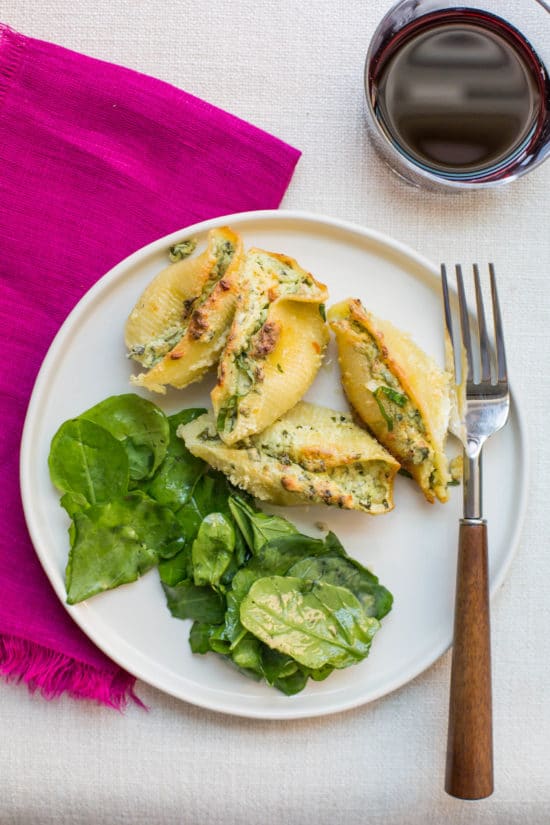 Fork on a plate with salad and Spinach and Cheese Stuffed Shells.