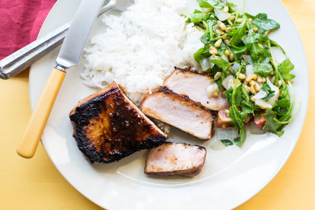 Korean Pork Chop, rice, and salad on a plate with silverware.
