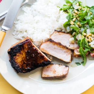 Korean Pork Chop, rice, and salad on a plate with silverware.