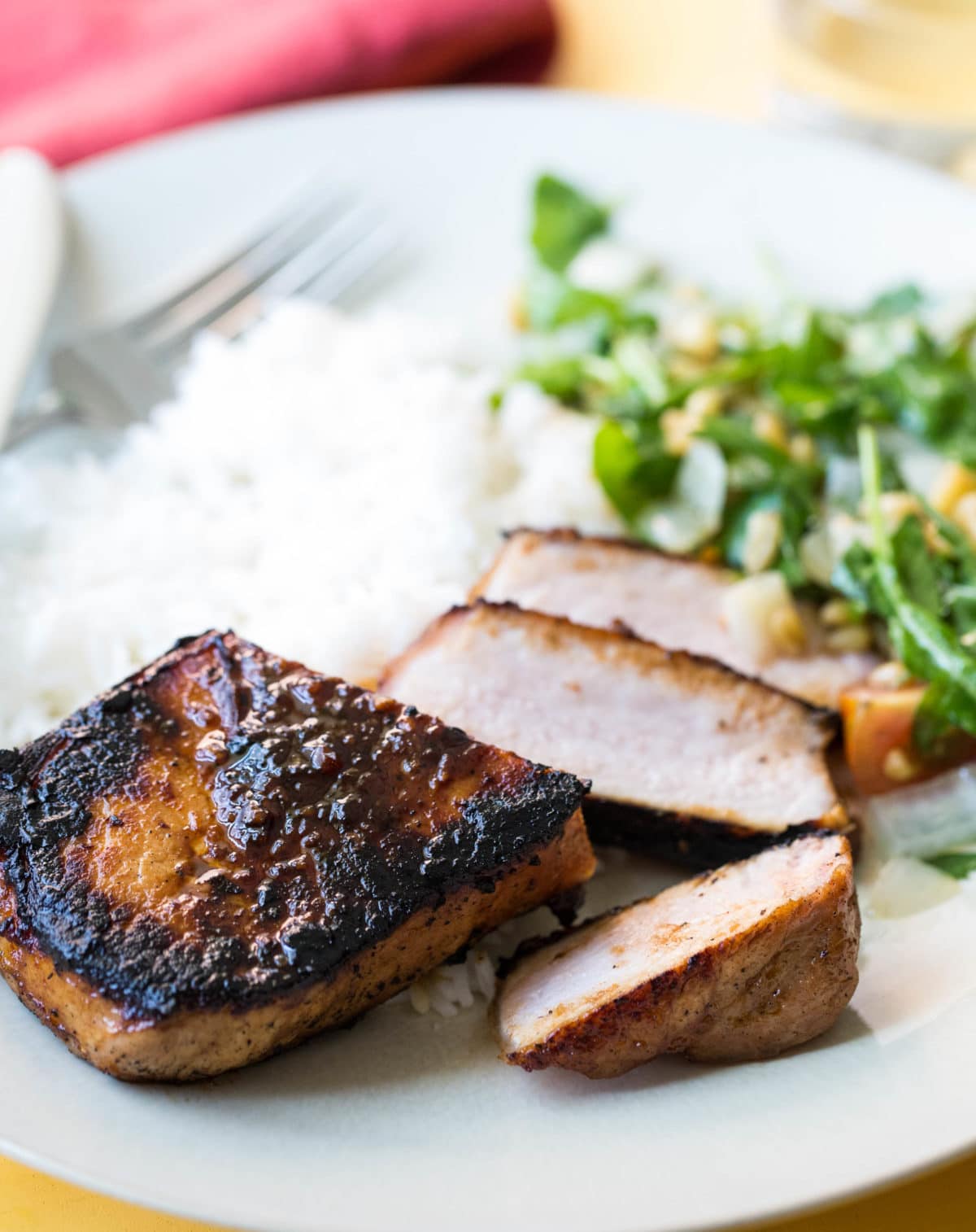 Sliced Korean Pork Chop with rice and salad on a plate.