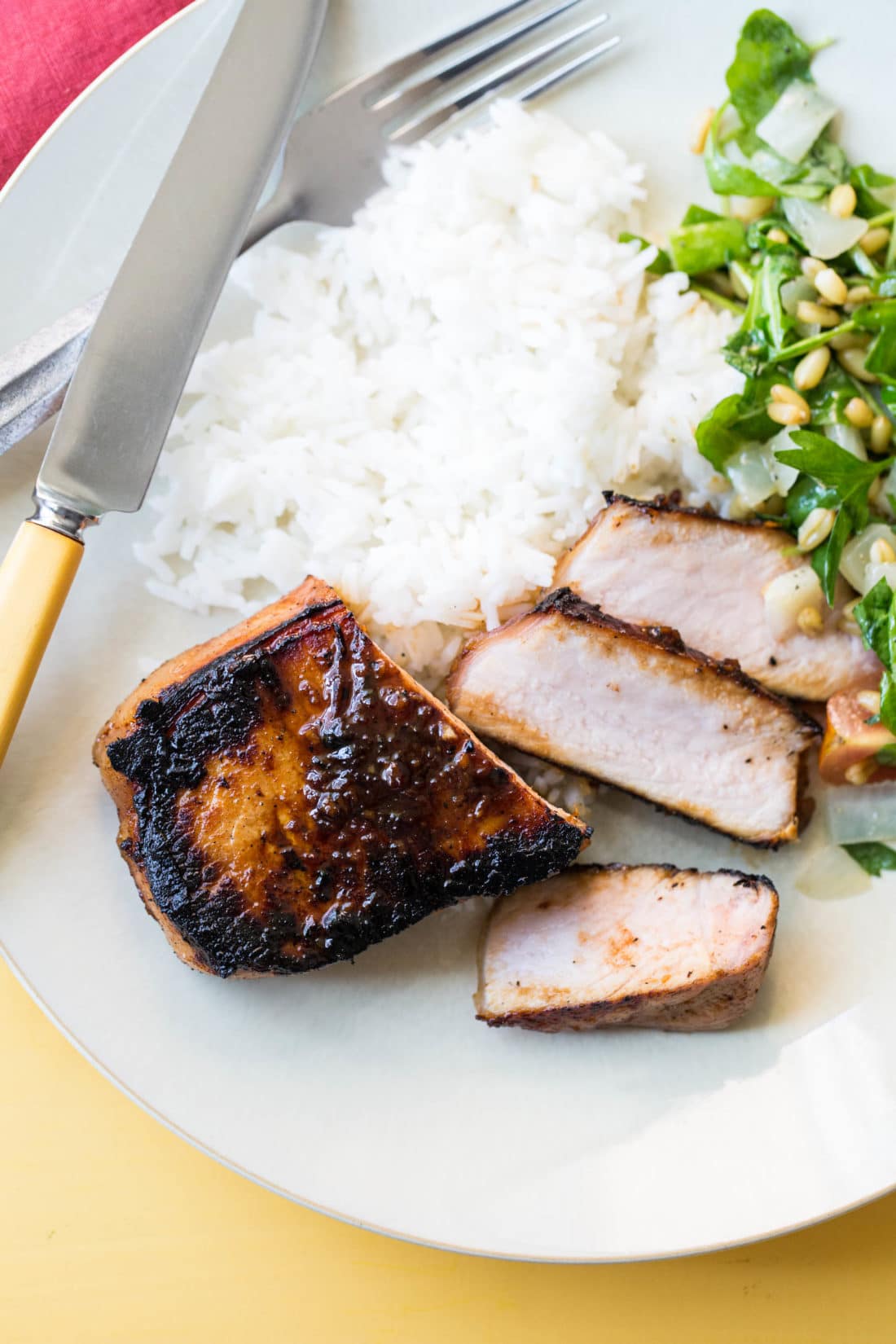 Korean Pork Chops, rice, and salad on a palte.