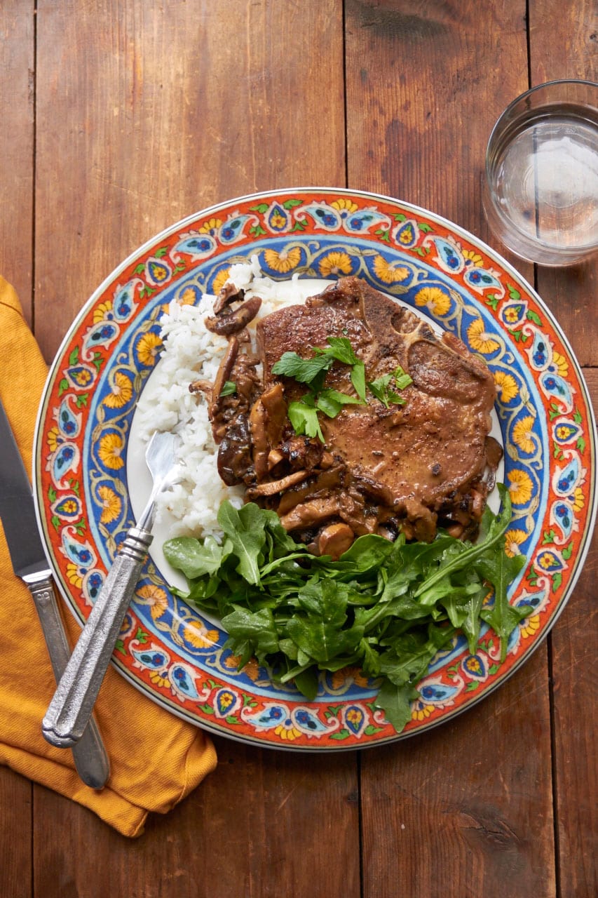 Pan Seared Pork Chops with Marsala and Mushroom Cream Sauce on colorful plate.