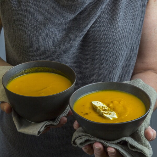 Woman holding two bowls of Indian Butternut Squash-Carrot Soup .