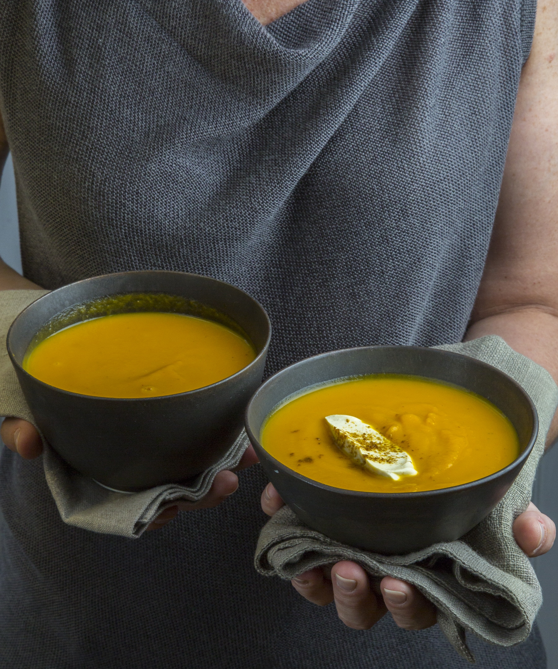 Woman holding two bowls of Indian Butternut Squash-Carrot Soup .
