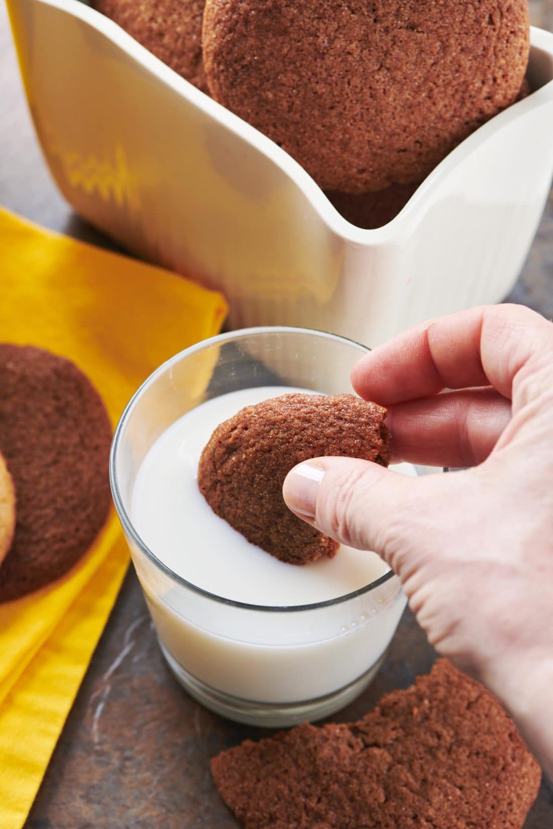 Woman dipping a Molasses Cookie into milk.
