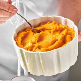 Serving bowl of Garlic Mashed Sweet Potatoes with spoon.