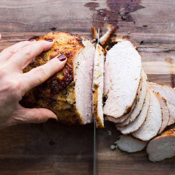 Slicing Lemon-Garlic Roasted Turkey Breast on cutting board.