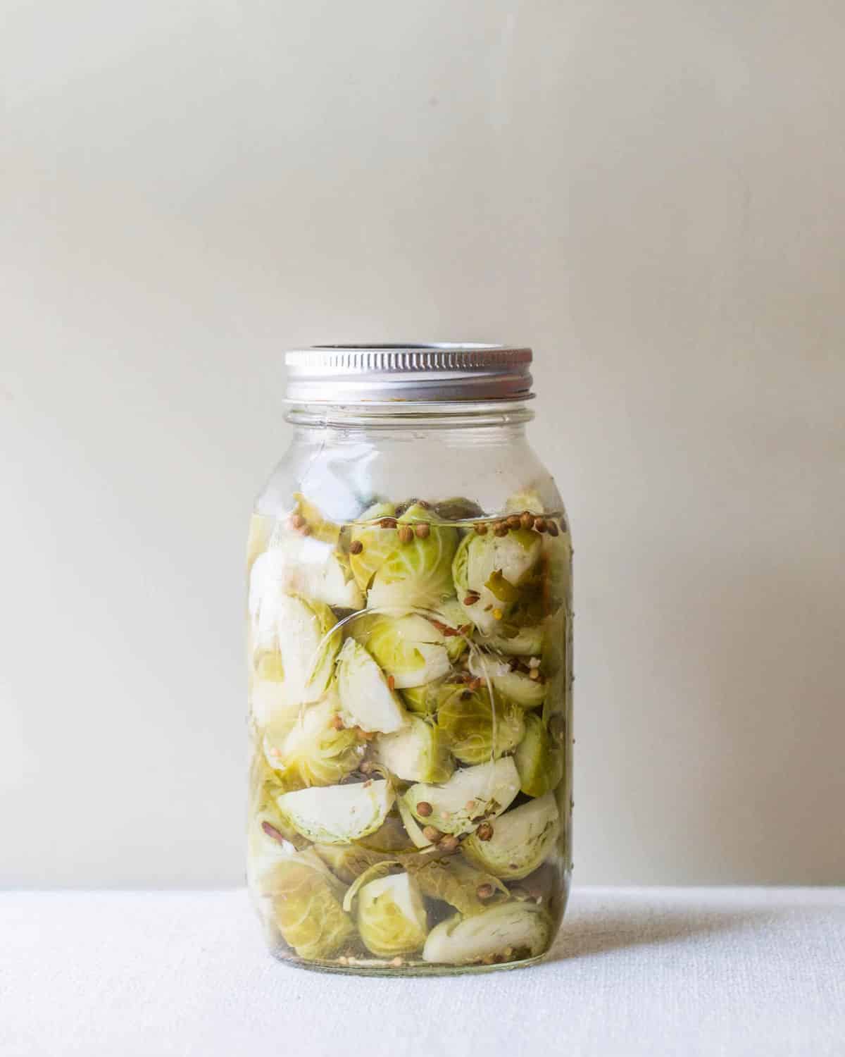 Pickled Brussels sprouts in jar on table.