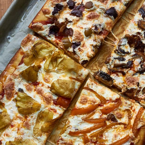 Sliced Pizza Quattro Stagioni on baking sheet.