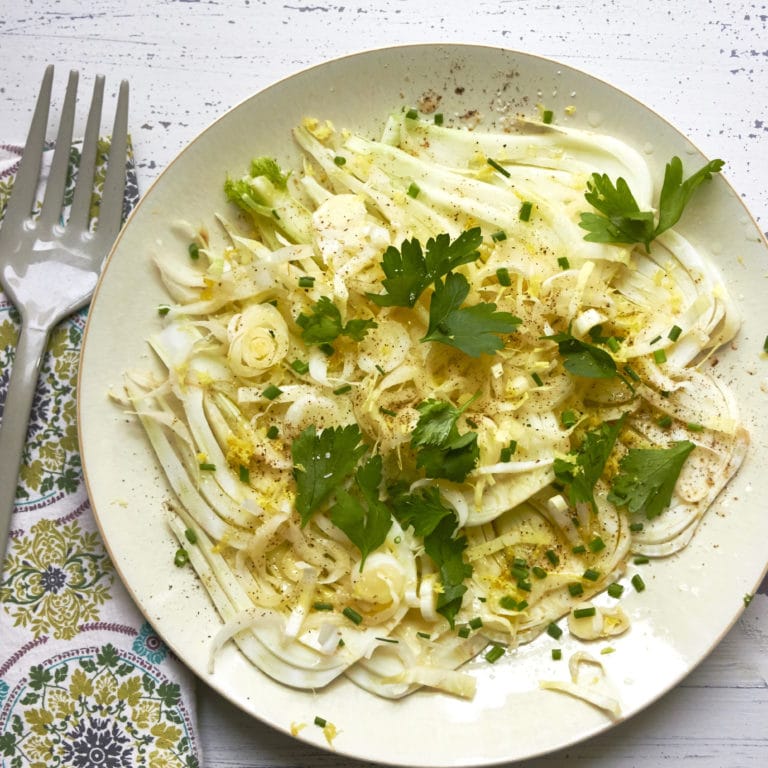 Fennel and Endive Salad on white plate with fork and napkin.