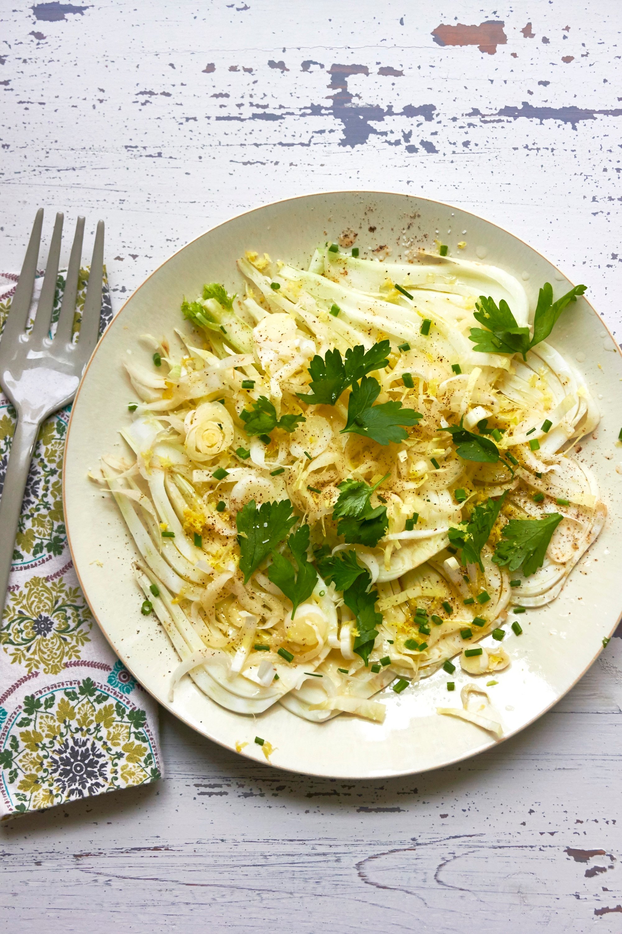 Fennel and Endive Salad on white plate with fork and napkin.