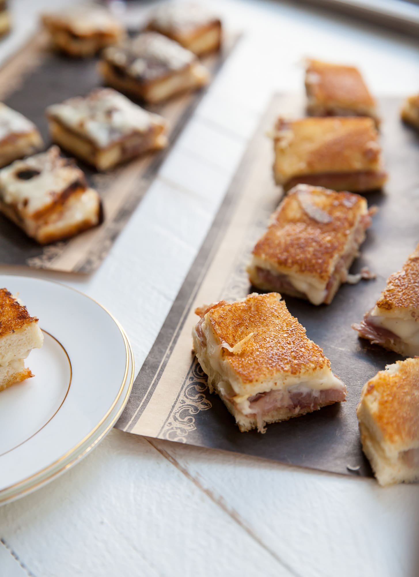 Mini croque monsieurs with prosciutton on trays.