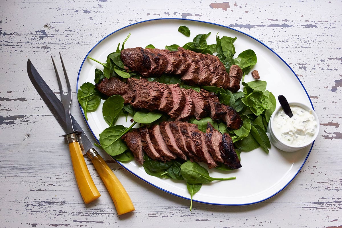 Sliced petit filet on plate with bowl of homemade herb dip.
