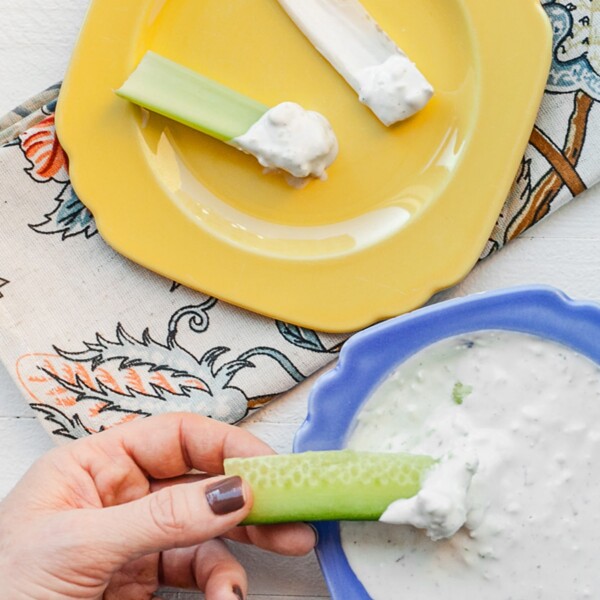 Woman dipping cucumber in Blue Cheese Dip.