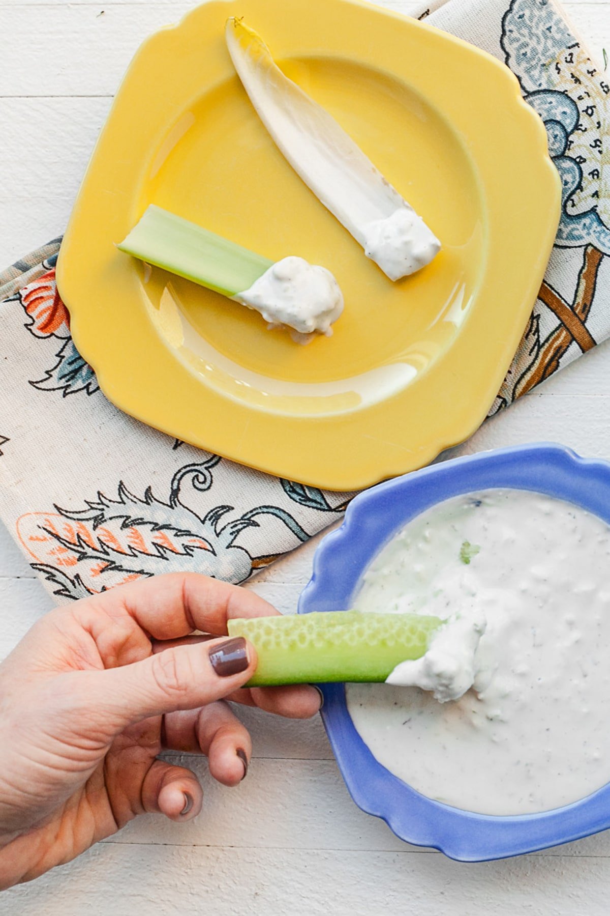 Celery dipped in blue cheese dressing on a plate.