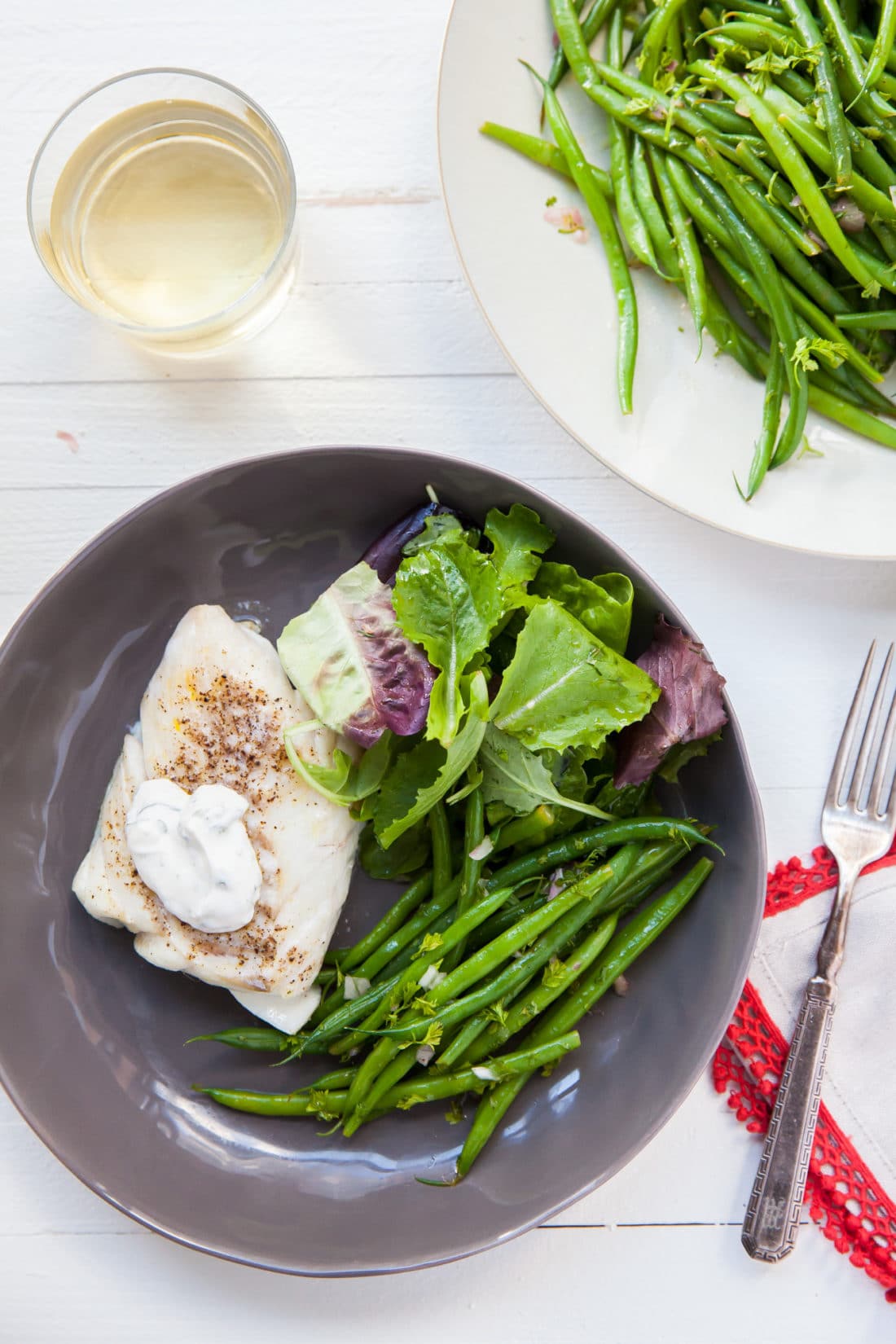 Cod with Fresh Herb Sauce on a plate with salad and green beans.