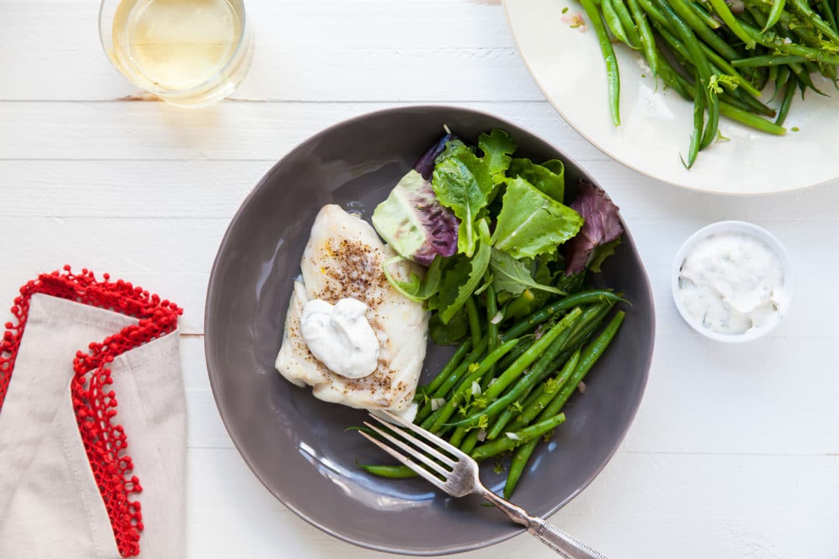 Plate of salad, green beans, and Cod with Fresh Herb Sauce.