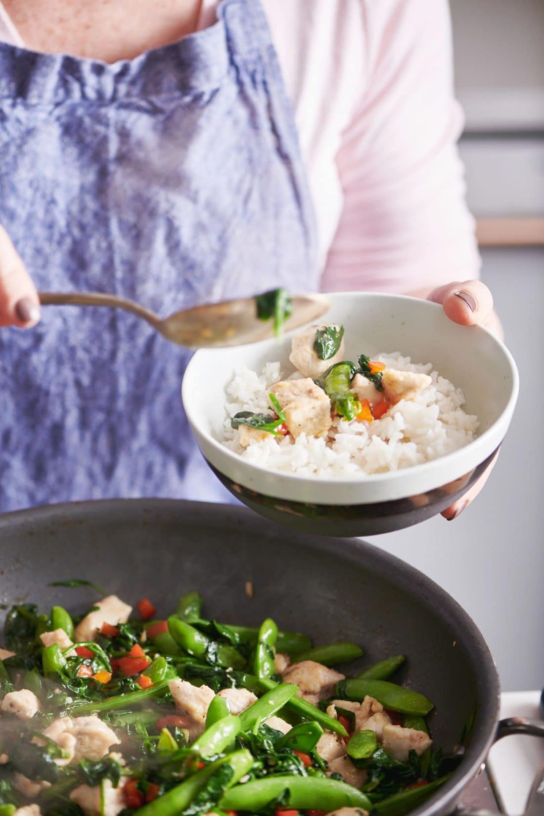 Woman scooping Chicken and Spinach Stir-Fry with Ginger and Oyster Sauce over rice.