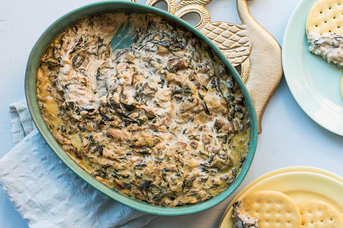 Hot Creamy Mushroom and Spinach Dip in a bowl and on crackers.