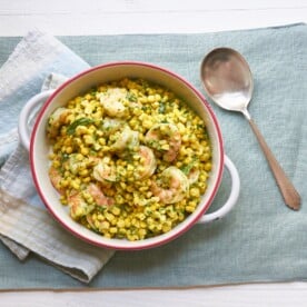 Spoon next to a bowl of Shrimp and Corn Salad with Basil Dressing.