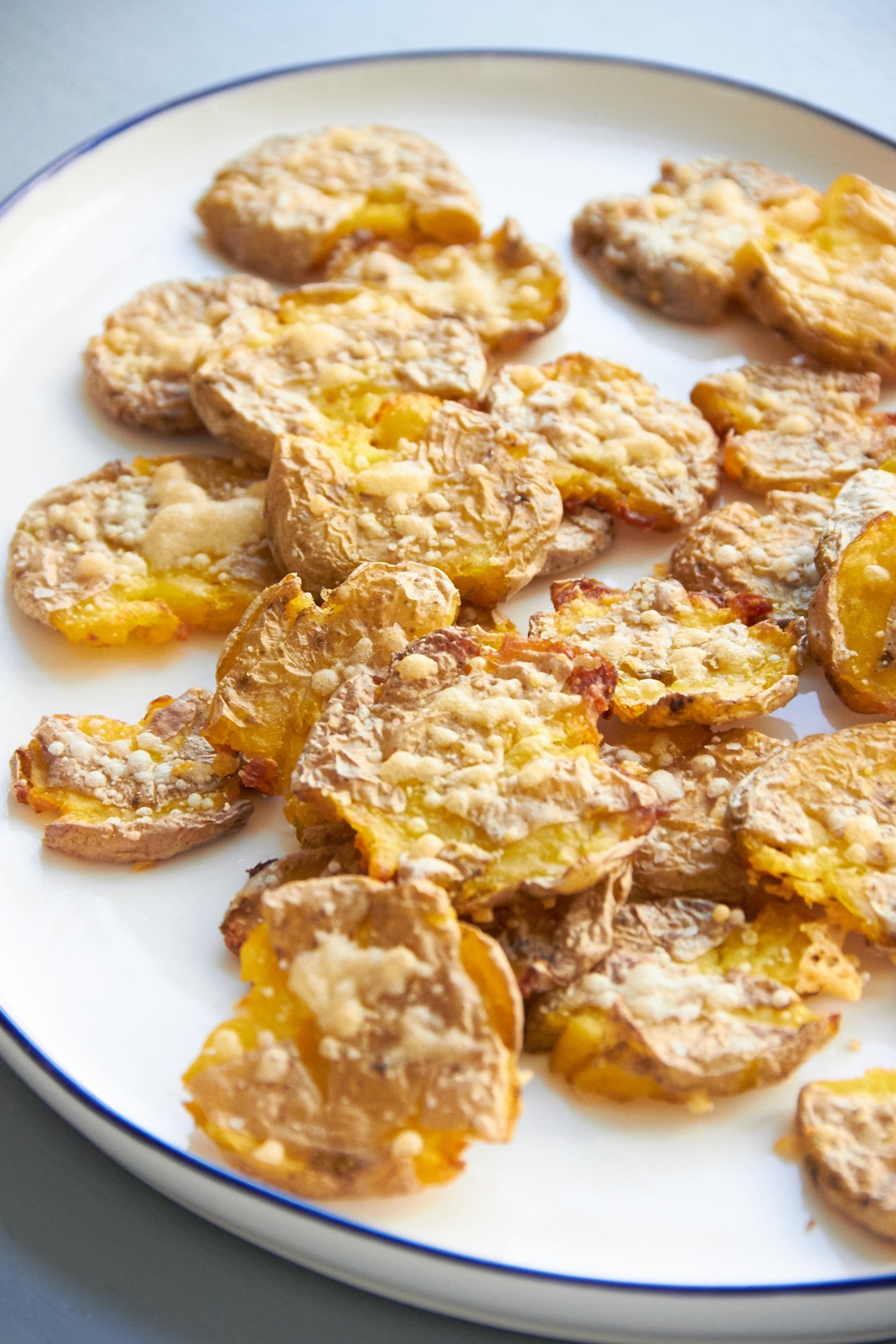Oblong, blue-rimmed serving platter of Smashed Roasted Baby Potatoes.